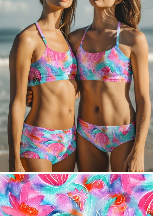 Womens swimwear featuring Lily Lover pattern, bold, painterly water lilies in pink, teal, lilac, and yellow with soft white detailing, creating a striking design