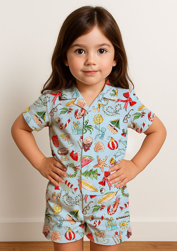 Child wearing colourful summer christmas pjs - playful beach christmas pattern with a blue background