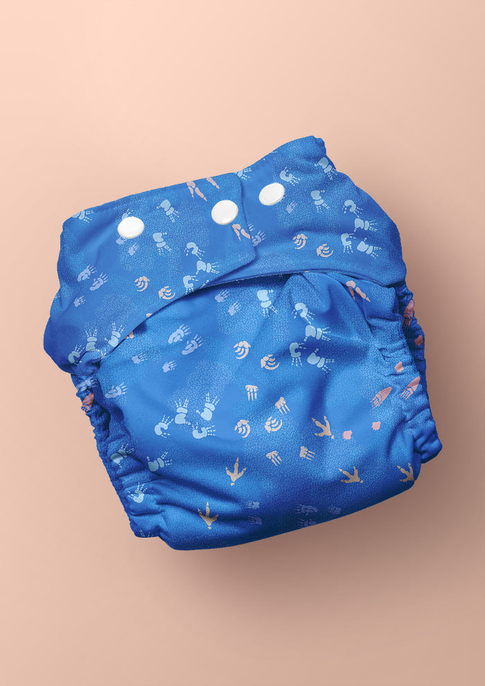 Blue swim nappy diaper featuring whimsical Australian wildlife footprints – kangaroo, echidna, wombat, and more – inspired by bushland trails and nature’s stories. Surface pattern design Australia.