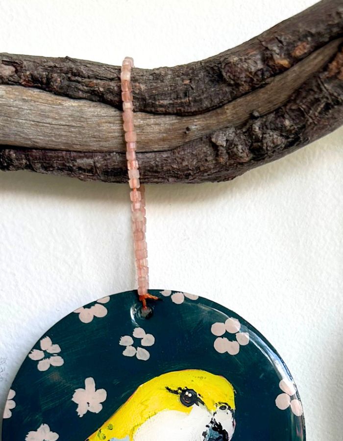 Detail of Little Yella ornament showing glossy resin surface and handmade beaded hanger