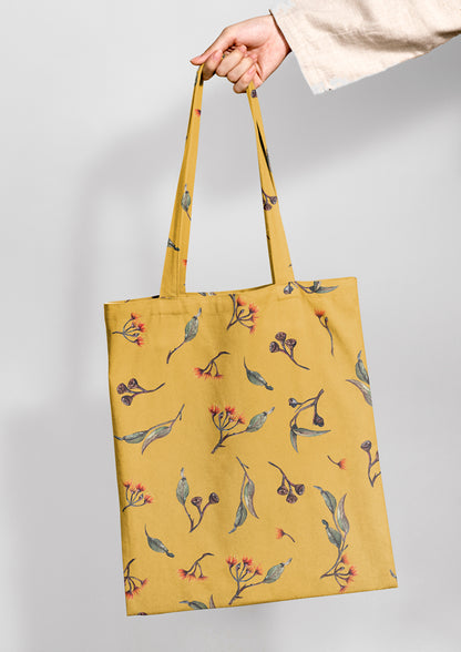 Tote bag featuring Eucalypt Echo pattern in a mustard palette, flowing eucalyptus elements spaced widely for dramatic impact on wallpaper or large fabric prints.