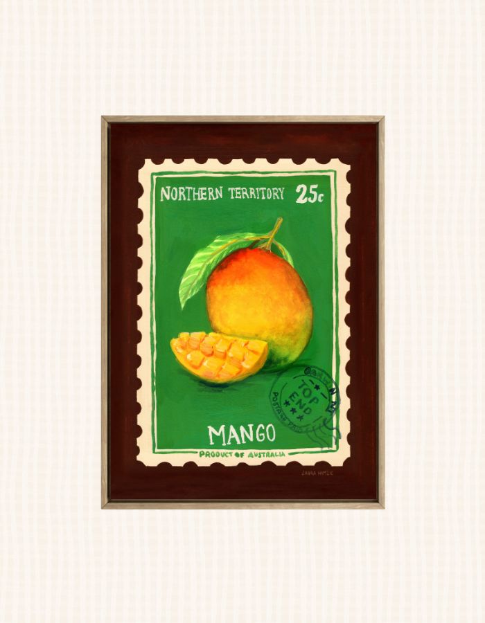 A framed vintage-style mango illustration print with a green background, a whole mango and a sliced mango, and the text 'NORTHERN TERRITORY 25c' and 'MANGO'. The print is mounted in a dark brown frame against a light off-white textured background.