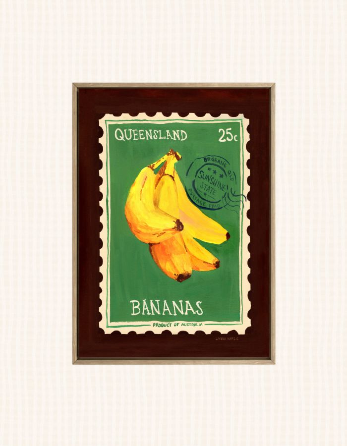 A framed art print depicting a vintage Queensland 25c banana stamp, featuring a bunch of yellow bananas on a green background with a dark brown frame.