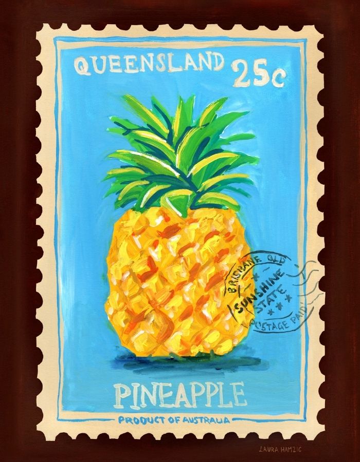 A framed art print depicting a painted pineapple on a blue stamp-like background with the words 'QUEENSLAND 25c' at the top and 'PINEAPPLE Product of Australia' at the bottom, shown against a dark brown frame.