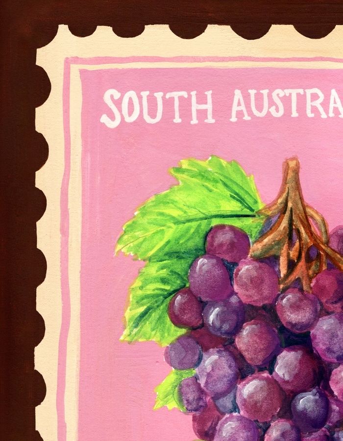A close-up of a painted fruit artwork showing a bunch of purple grapes with green leaves on a pink background, with partial text reading 'SOUTH AUSTRAL' and a dark brown scalloped border around the edges.