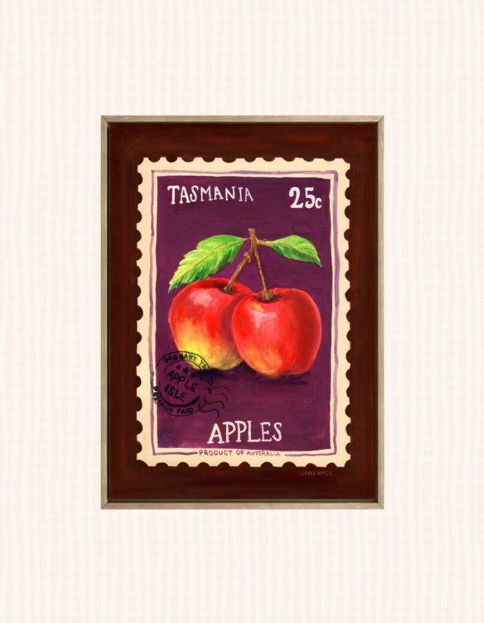 A framed art print depicting two red apples with green leaves on a purple stamp-like background, labeled 'TASMANIA 25c APPLES'. The print is housed in a dark brown wooden frame with a gold-toned inner border, set against a light cream textured background.