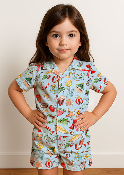 Child wearing colourful summer christmas pjs - playful beach christmas pattern with a blue background